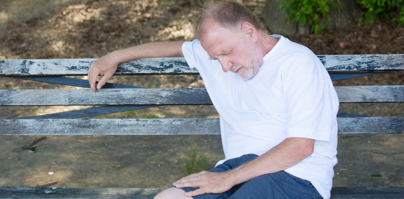 Older gentleman sitting on a bench expressing fatigue and weakness