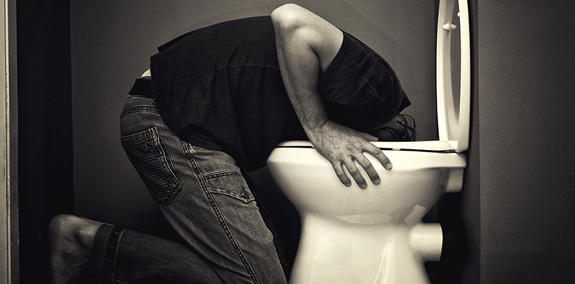 Man is persistently vomiting in a tiolet