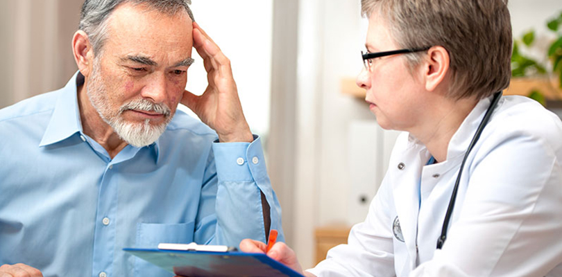 Older gentleman sits with doctor explaining symptoms to him