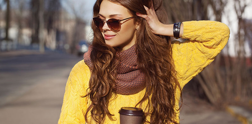 A young woman is walking with a coffee in her hand