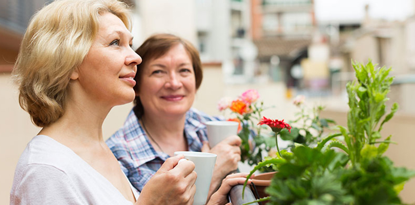 Two woman outside enjoying a cup of coffee