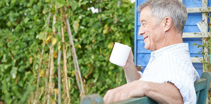 Older gentleman enjoying his coffee in his garden