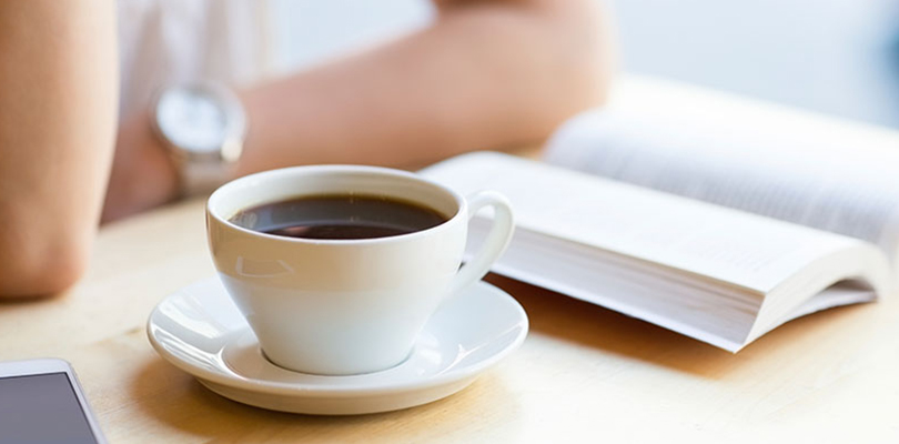 Woman sitting with a cup of coffee and book