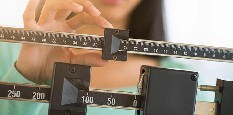 Woman is standing on a sliding scale and determining her weight