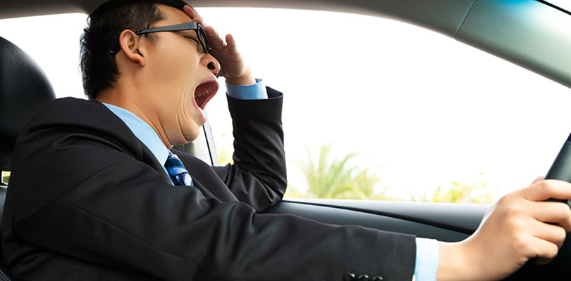 A man is yawning behind the wheel