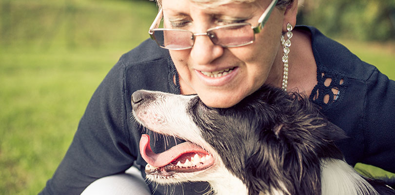 An older woman is nuzzling with her dog