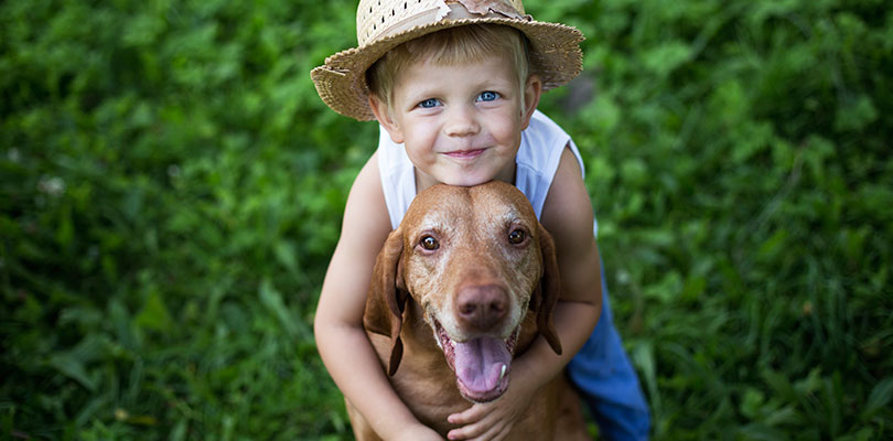 A child is hugging his dog