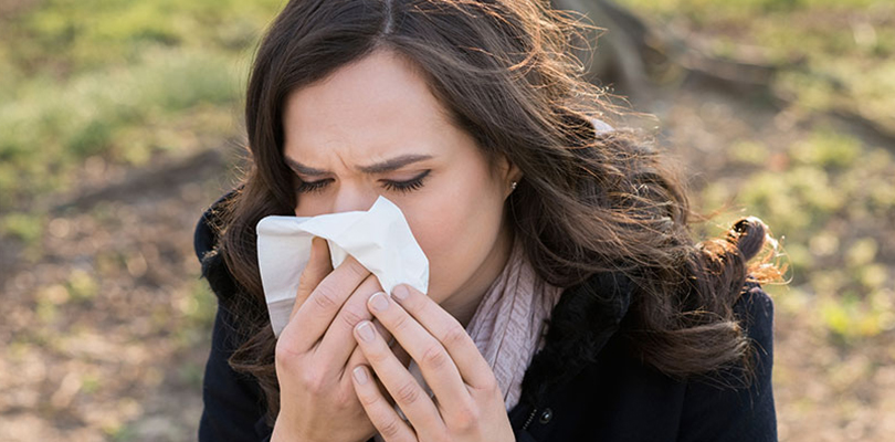 A woman is blowing her nose into a tissue