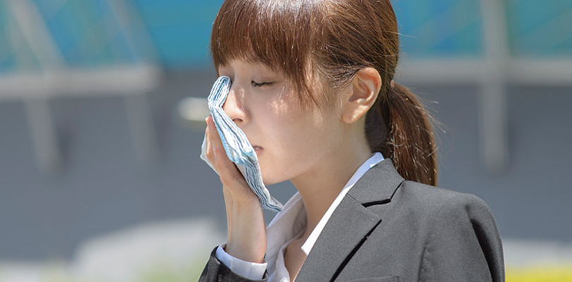 Young woman is holding a cloth to her sweaty face