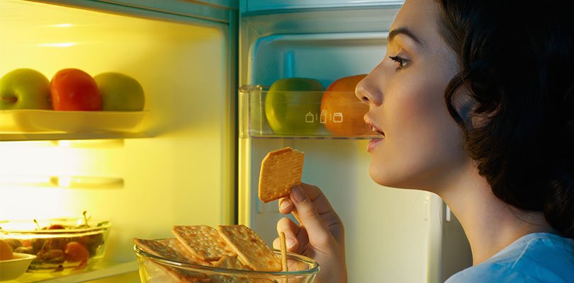 A woman is looking into the fridge for some snacks