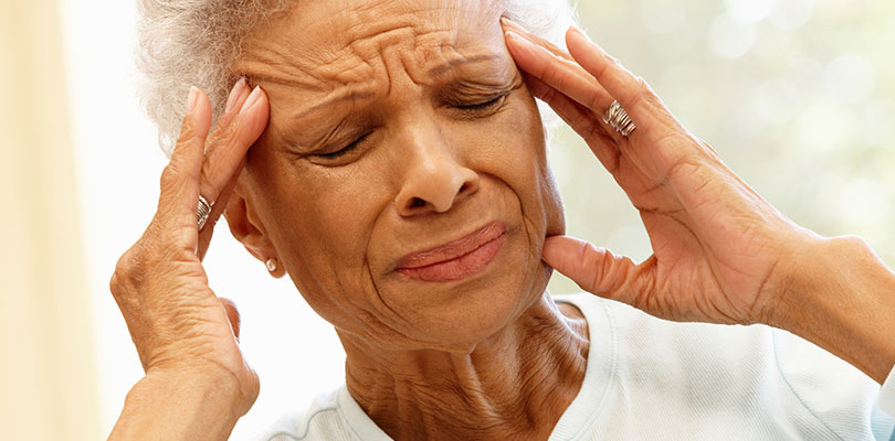 An older woman is experiencing extreme pain in her head