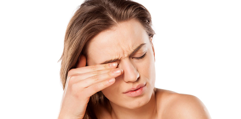 A woman places her fingers on top of her eyelid