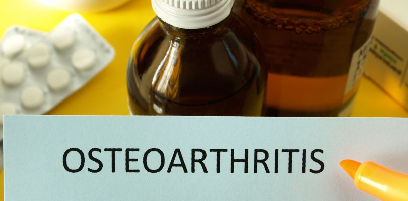 The word "Osteoarthritis" is printed on a sheet of paper with medications in the background