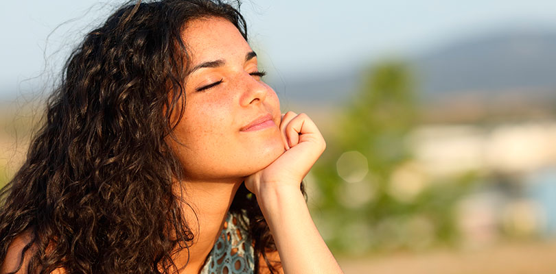 Young woman smiling with her face in the sun