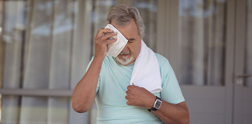 Senior man wiping sweat off his face with towel