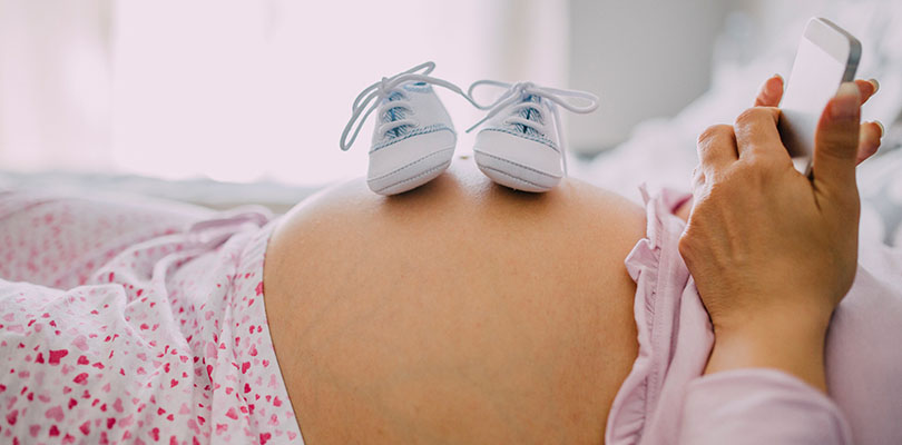 A mother at the last stage of her pregnancy has shoes on her belly