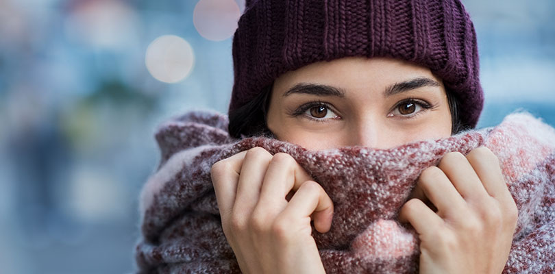 A woman is holding her scarf to her face