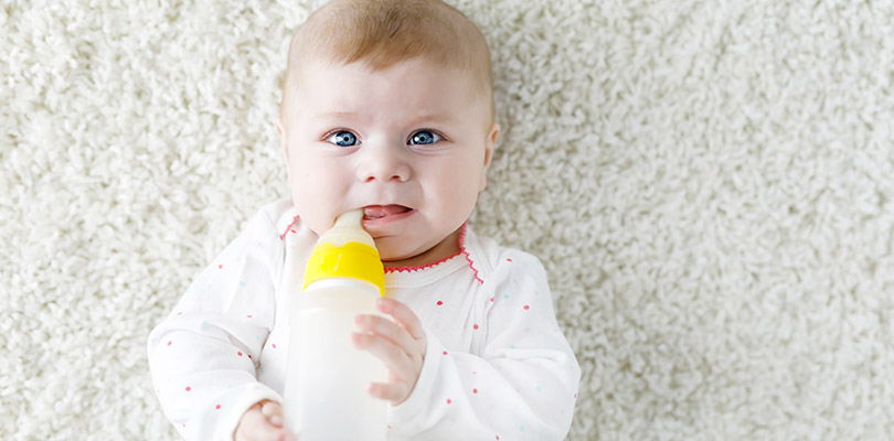 A baby is drinking from their bottle