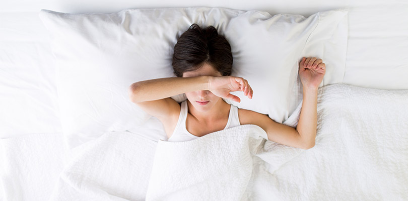 A woman is laying in bed due to chronic fatigue syndrome