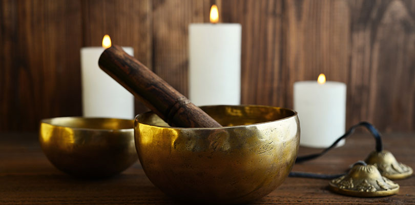 Candles, ting bowls and other meditation tools are on a table.