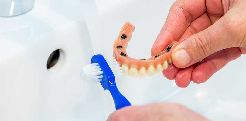 Cleaning dentures in a sink, with a special denture brush