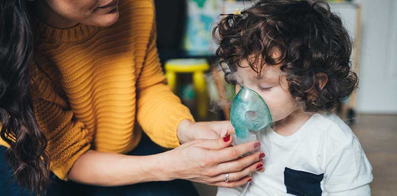 A woman holding an oxygen mask up to a child.