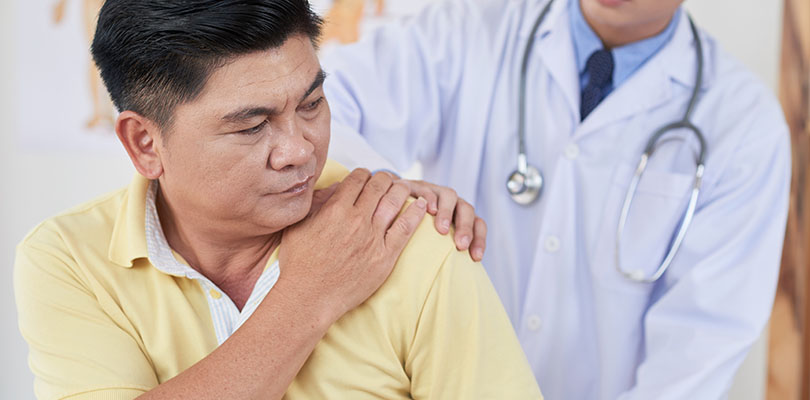 Senior Asian man visiting doctor as he is suffering from pain in shoulder