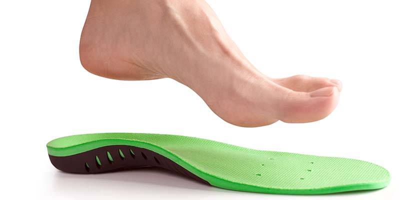 Someone's foot over a green shoe insole.